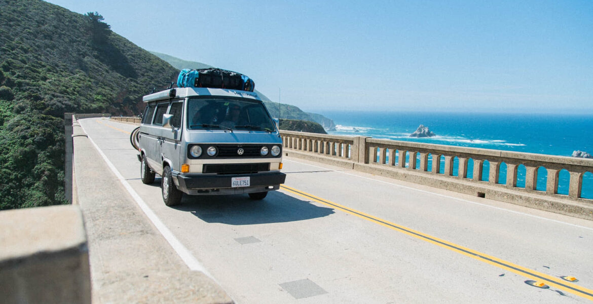 van crossing bridge over body of water
